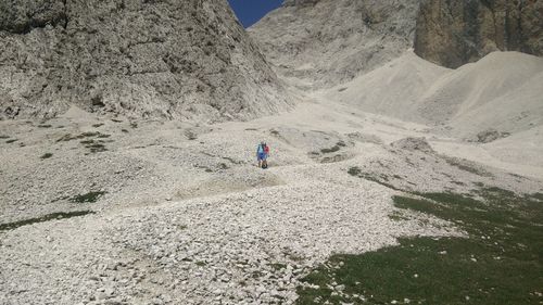 Rear view of man climbing on mountain against sky