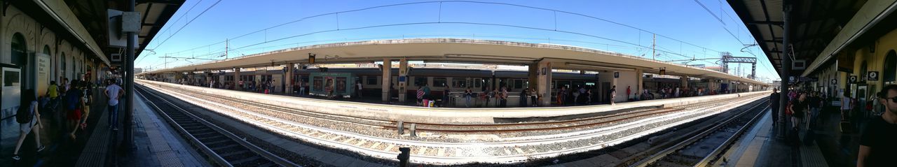 People at railroad station platform against clear sky