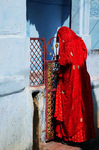 Rear view of a woman standing against the wall