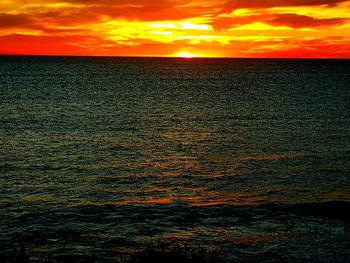 Scenic view of sea against dramatic sky during sunset