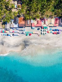 Aerial view of a jungle lined beach. colorful roofs and umbrellas line the vibrant beach in bali