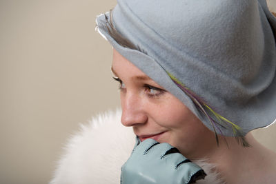 Close-up of young woman looking away against wall