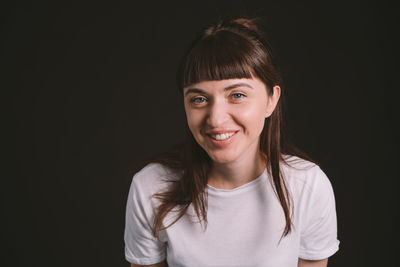 Portrait of smiling woman against black background