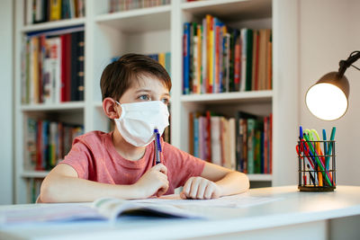 Boys wearing flu mask while studying at home