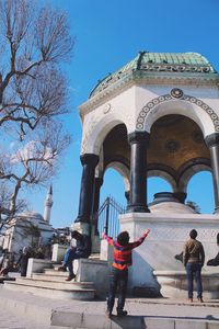 People walking outside temple against clear sky