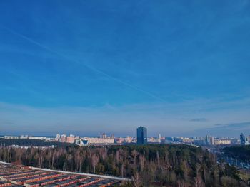 Aerial view of buildings in city against blue sky