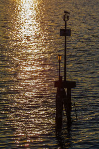 Silhouette man by sea against sky during sunset