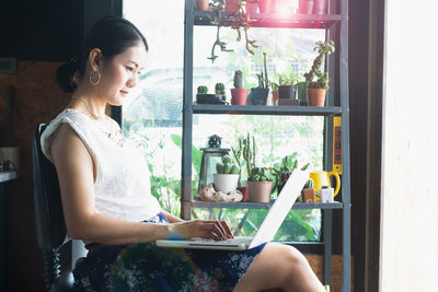 Side view of young woman holding window at home