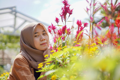 Beautiful muslim woman taking photo with flowers by her side