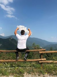 Rear view of man on mountain against sky