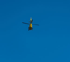 Low angle view of helicopter against clear blue sky