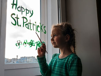 Portrait of girl standing against window