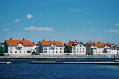 Residential buildings by sea against blue sky