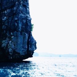 Rock formation in sea against clear sky