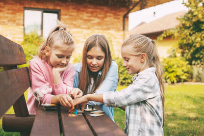 Friends have fun and play a wooden board game with colored chips in blue, red, green, yellow