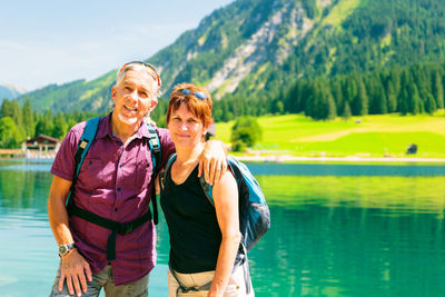 Portrait of smiling young man standing against lake
