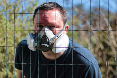 Portrait of man wearing mask against fence