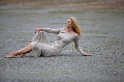 Side view of woman sitting on sand at beach