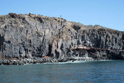 Rock formations in sea against clear sky