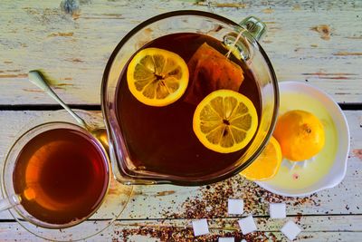 Black tea, a cup of black tea, manual squeezer with lemons. a jug of black tea and cubes of sugar