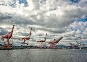 Boats at harbor against cloudy sky