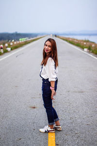 Portrait of smiling young woman standing on road