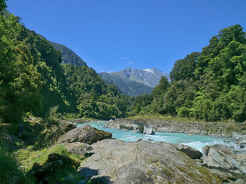 Scenic view of river by mountains against sky