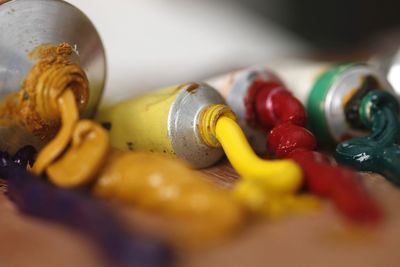 Close-up of colorful paints spilled from tubes on wooden table