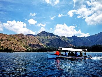 People on boat in lake against sky
