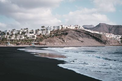 Scenic view of beach by buildings against sky