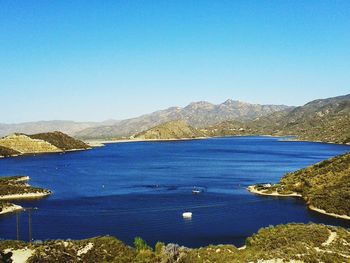 Scenic view of sea and mountains against clear blue sky