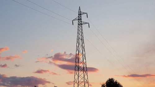 Low angle view of electricity pylon against cloudy sky