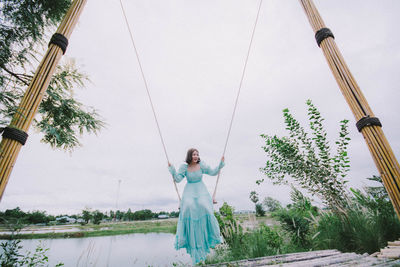 Full length of woman sitting on swing against sky