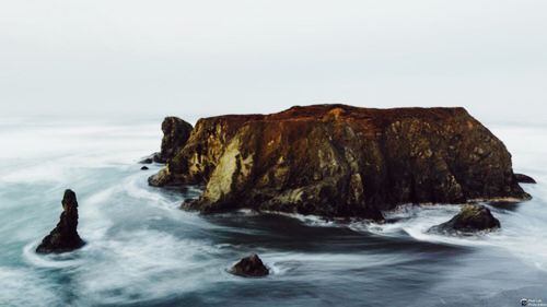 Scenic view of rocks in sea against sky