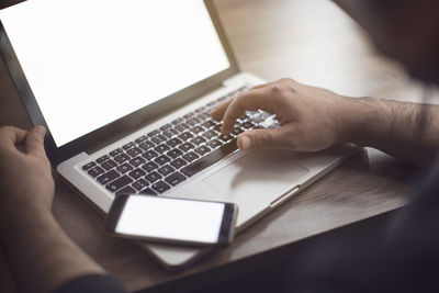 Midsection of man using laptop on table