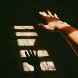 Cropped image of hand with shadow on wall