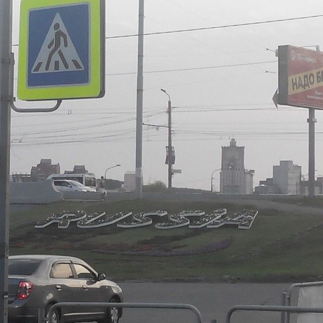 transportation, land vehicle, car, communication, mode of transport, text, road sign, road, street, building exterior, architecture, western script, built structure, city, information sign, guidance, power line, sign, clear sky, street light