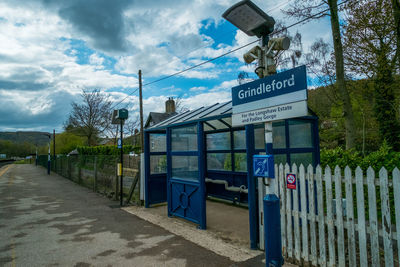 Information sign on road by trees against sky