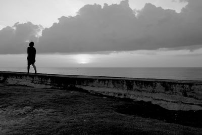 Silhouette man standing on beach against sky