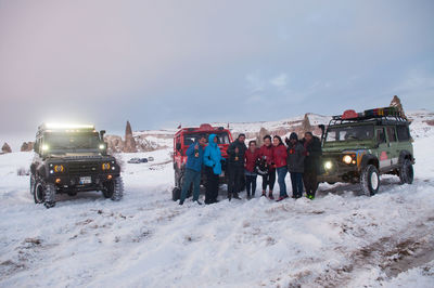 People on snow covered field against sky