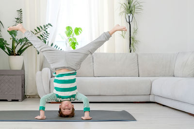 Boy practicing headstand on mat at home