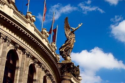 Low angle view of angel statue against blue sky