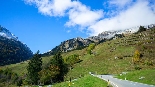 Scenic view of road by mountains against sky