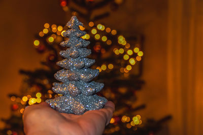 Close-up of hand holding illuminated christmas tree