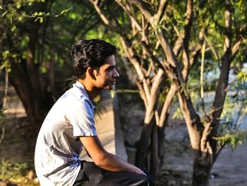 Side view of young man standing in forest