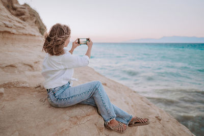 Man photographing while sitting on beach