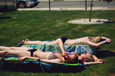 Friends sunbathing on grassy field in yard