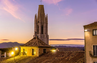 Illuminated building against sky during sunset