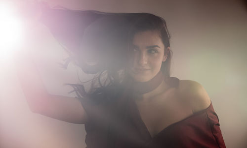 Portrait of young woman standing against gray background