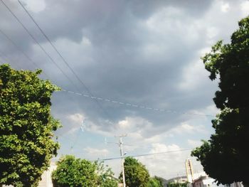 Low angle view of electricity pylon against cloudy sky